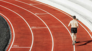 A runner on the curve of a running track, seen from behind